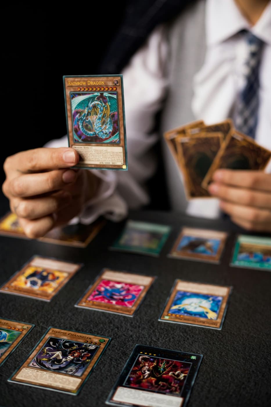 Joueur de Yu-Gi-Oh! présentant une carte Rainbow Dragon au-dessus du tapis de jeu